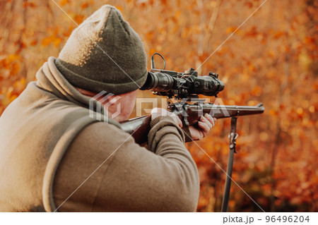 Portrait of hunter or ranger with gun or rifle in the forest looking out or hunting of some venison, hunting period, autumn season, hunting and people concept 96496204