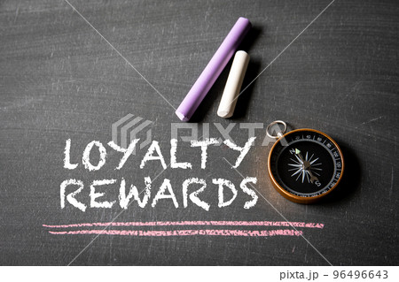 Loyalty Rewards. Text, compass and colored pieces of chalk on blackboard background Loyalty Rewards. Text, compass and colored pieces of chalk on blackboard background 96496643