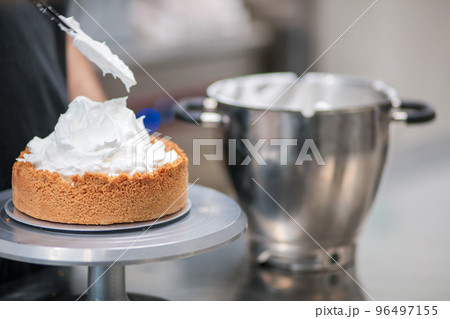 pastry chef designer filling a pie crust with lemon flavour meringue mousse cheese cream with spatula pastry chef designer filling a pie crust with lemon flavour meringue mousse cheese cream with spatula 96497155