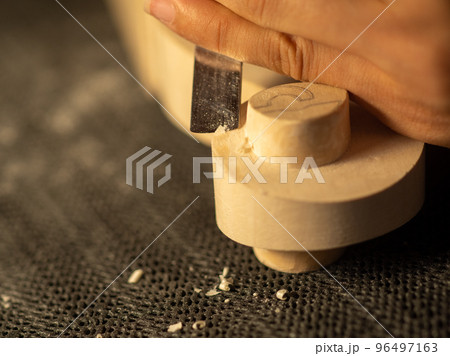 luthier artisan maker sculpting and carving violin scroll and neck with chisel 96497163