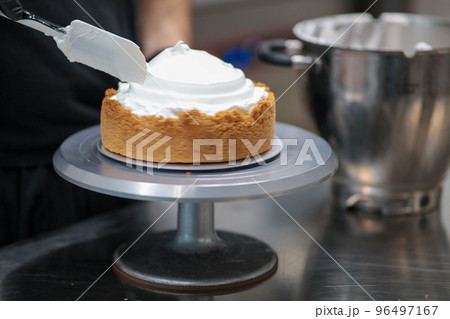 pastry chef designer filling a pie crust with lemon flavour meringue mousse cheese cream with spatula pastry chef designer filling a pie crust with lemon flavour meringue mousse cheese cream with spatula 96497167