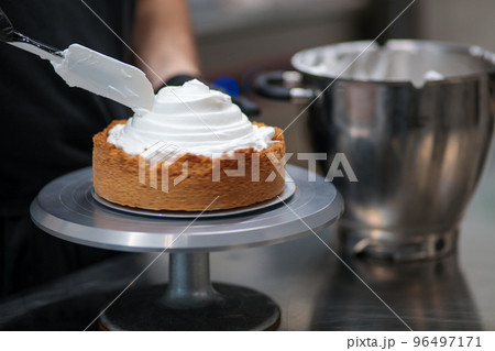 pastry chef designer filling a pie crust with lemon flavour meringue mousse cheese cream with spatula pastry chef designer filling a pie crust with lemon flavour meringue mousse cheese cream with spatula 96497171
