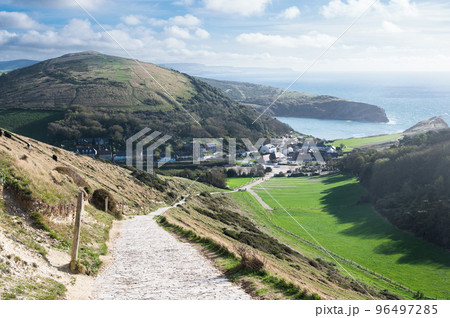 Stone road to Durdle door in Lulworth, part of Jurassic Coast World Heritage Site, view of the seaside cottages and Lulworth Cove in the background, selective focus 96497285