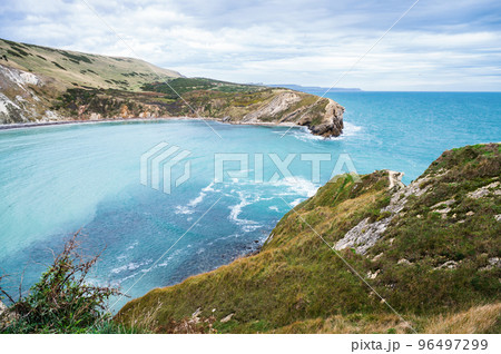 Beautiful views of Lulworth Cove in Dorset, United Kingdom. Part of Jurassic Coast World Heritage Site, view of stone cliffs and blue sea, selective focus Beautiful views of Lulworth Cove in Dorset, United Kingdom. Part of Jurassic Coast World Heritage Site, view of stone cliffs and blue sea, selective focus 96497299