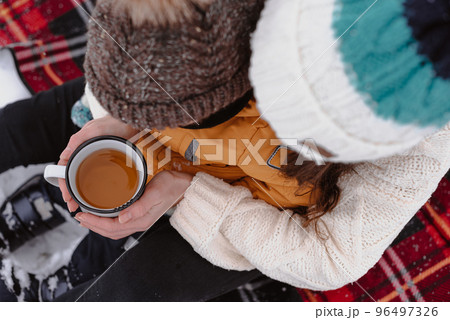 Mother and child on a winter walk outdoors drinking tea 96497326