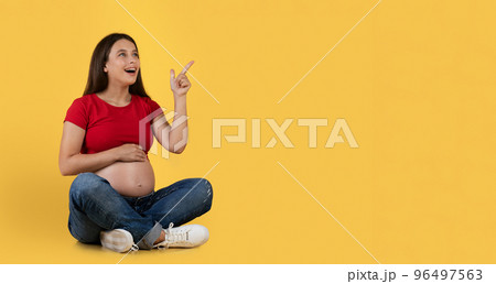 Amazed Young Pregnant Woman Having Idea, Pointing Up Finger And Smiling 96497563