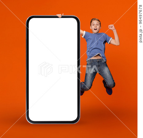 Online Ad. Surprised Teen Boy Holding Huge Blank Smartphone And Jumping Online Ad. Surprised Teen Boy Holding Huge Blank Smartphone And Jumping 96497678
