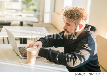 Close-up male guy portrait resting in coffee shop chatting in social networks skilled freelancer enjoying remote job typing publication for web blog on laptop 96499493
