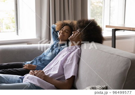 Beautiful carefree African teenage couple relaxing at home 96499577