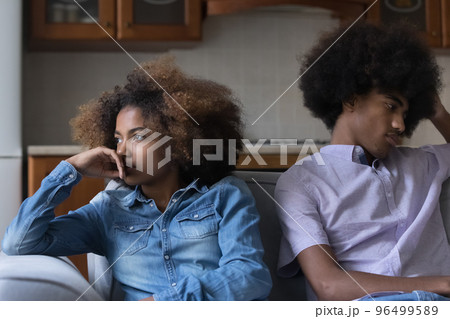 Sad African couple sit on sofa feel upset after quarrel 96499589