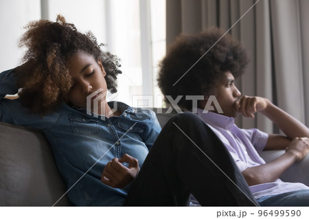 African couple sit on sofa apart after quarrel African couple sit on sofa apart after quarrel 96499590