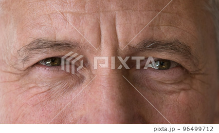 Mature man staring at camera, close up upper face view Mature man staring at camera, close up upper face view 96499712