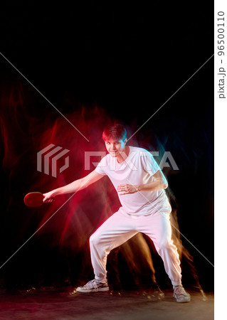 young man playing table tennis in mixed neon light 96500110