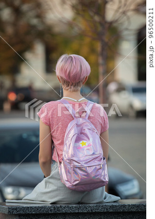 Ukraine. The city of Kharkov. September 10, 2019. Girl in pink clothes with a pink haircut. Lonely girl, view from the back. Ukraine. The city of Kharkov. September 10, 2019. Girl in pink clothes with a pink haircut. Lonely girl, view from the back. 96500211