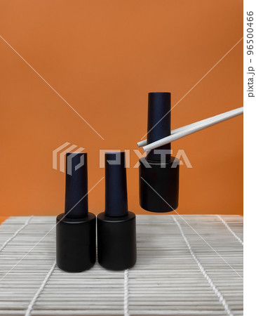 Black bottles of nail polish on a orange background Black bottles of nail polish on a orange background 96500466