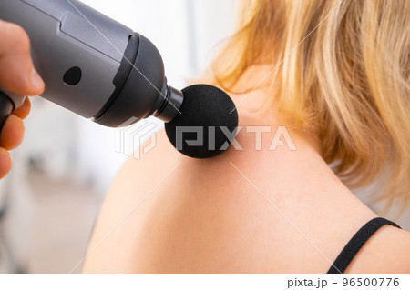 A therapist massaging a womans neck using a massage gun. Physical therapy for recovery.  96500776