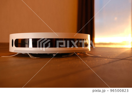 white vacuum robot cleaner close up with sunset light on the brown dalle with beautiful flares and dust around 96500823