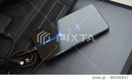Hands plug in portable solar panel charging smartphone by mutlipurpose cable, power bank, watches, laptops. Clean energy for using in camping or at home when NO electricity. 96500837