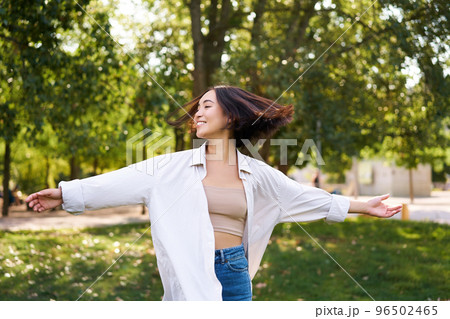 Freedom and people concept. Happy young asian woman dancing in park around trees, smiling and enjoying herself 96502465