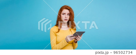 Close up Portrait young beautiful attractive tender ginger redhair girl happy smiling on digital table with wining something. Blue Pastel Background. Copy space 96502734