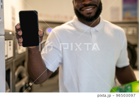 Joyous guy standing in a self-service laundry room Joyous guy standing in a self-service laundry room 96503097