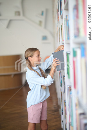 Cute girl searching for a book in the school library Cute girl searching for a book in the school library 96503164