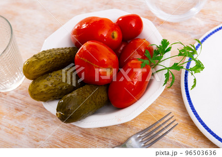 Pickled cucumbers and tomatoes served on plate with parsley Pickled cucumbers and tomatoes served on plate with parsley 96503636
