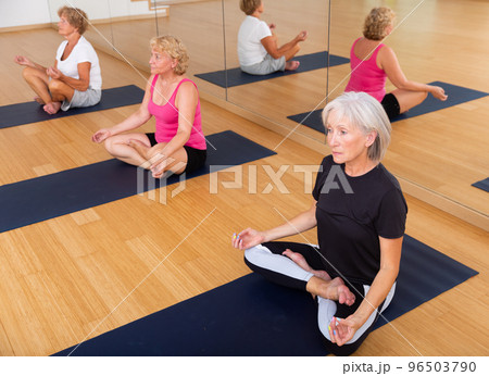 Mature woman making yoga meditation in lotus pose in fitness center Mature woman making yoga meditation in lotus pose in fitness center 96503790