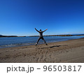 晴れた日の海岸で、両手足を広げてジャンプする男性 96503817