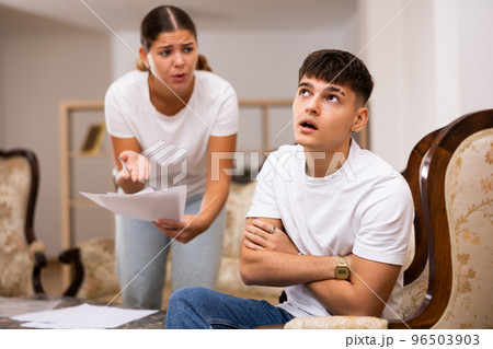 Upset young wife with documents swears at her husband 96503903