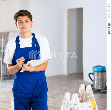 Repairman checking project documentation, planning renovation works in new apartment 96504246