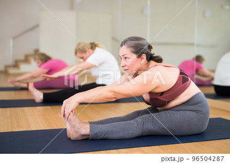 Active senior woman practicing yoga at group Active senior woman practicing yoga at group 96504287