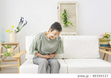 家で腹痛がする高齢者女性 96504537