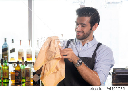 Young caucasian man is bartender cleaning and wipe glass with professional at counter. 96505776