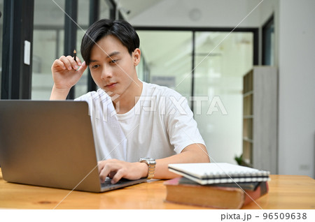 Smart Asian male concentrating doing his work project homework in campus library 96509638