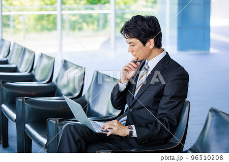 ロビーの椅子でノートパソコンを操作する男性 96510208
