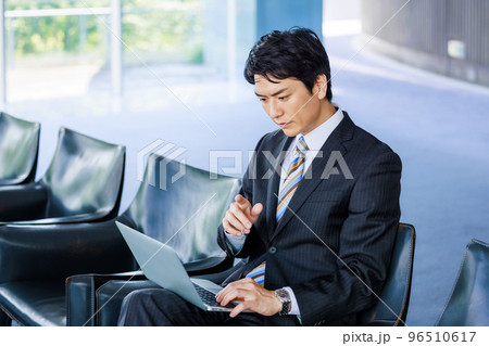 ロビーの椅子でノートパソコンを操作する男性 96510617