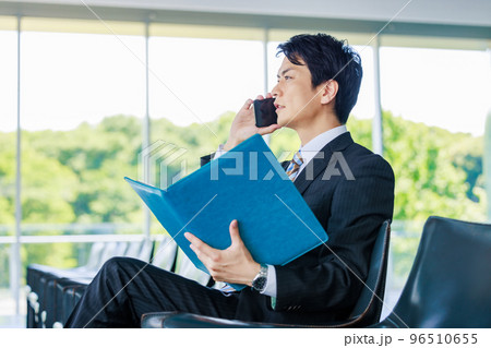 ロビーで資料を見ながら電話をするビジネスマン 96510655