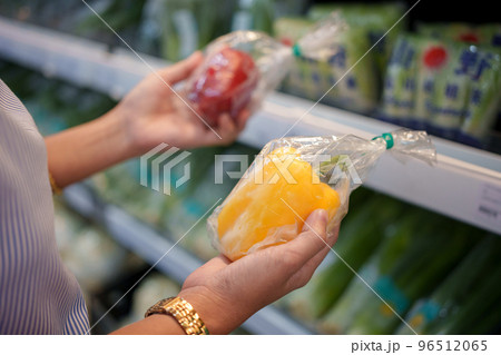 Woman holds yellow and red bell pepper in supermarket. 96512065