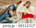 Cheerful mom and daughter play with Christmas lights on the floor by the fireplace, decorate the room for the holidays. The concept of Christmas and New Year 96512317