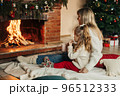 Family mother and child daughter hug and warm up on a winter evening by the fireplace, drink hot cocoa. Christmas Eve or New Year's Eve, Christmas holidays, Christmas time, family evening 96512333