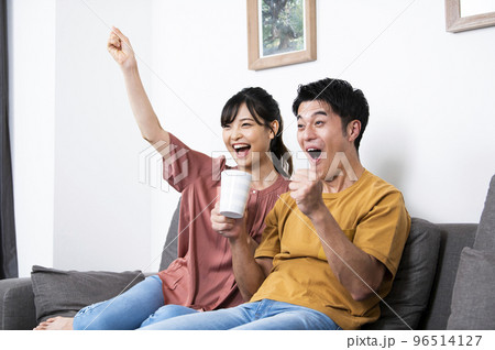 テレビでスポーツ観戦をする若い夫婦 テレビでスポーツ観戦をする若い夫婦 96514127