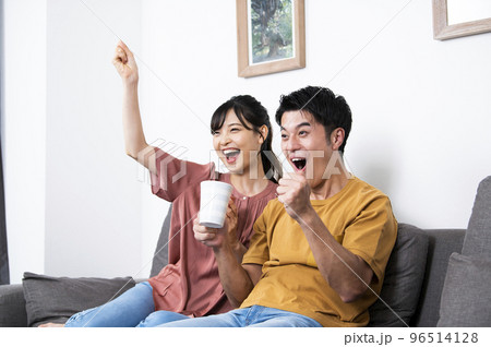 テレビでスポーツ観戦をする若い夫婦 96514128