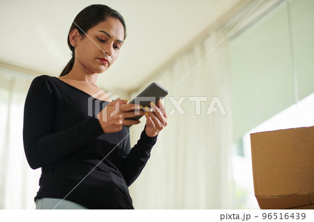 Serious young woman reading reviews on moving company before hiring 96516439