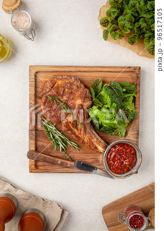 Portion of tomahawk steak with salad and sauce Portion of tomahawk steak with salad and sauce 96517105