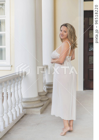 beautiful blonde in a nightgown on the pillared porch at home 96518220