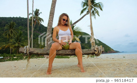 Attractive woman is swinging on a swing. Sexy hot erotic bad girl posing on the beach against the backdrop of the sea. Attractive woman is swinging on a swing. Sexy hot erotic bad girl posing on the beach against the backdrop of the sea. 96518417
