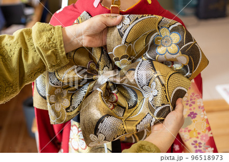 若い女性に振袖の着付けしているところ 96518973