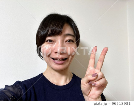ピースする笑顔の黒髪ショートヘア女性 96518981