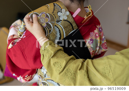 若い女性に振袖の着付けしているところ 96519009